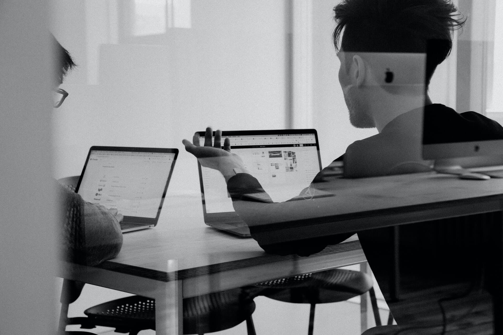 Two bloggers working on laptops at a desk.