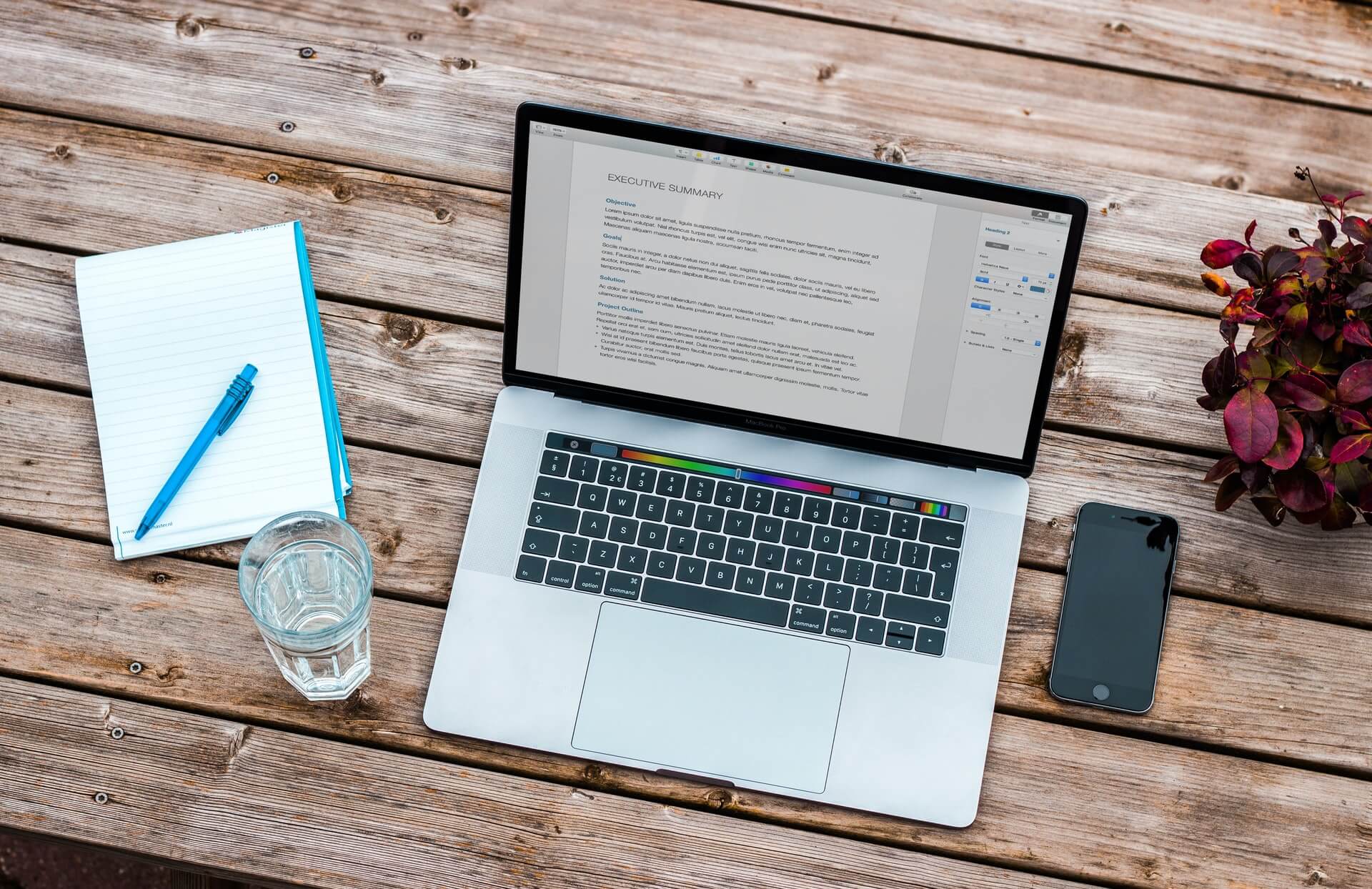 A laptop and phone on a wooden table for successful blogging.
