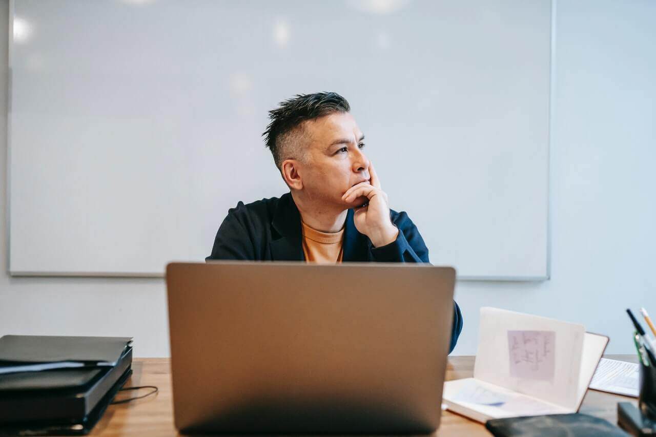 A man sitting at a desk with a laptop, following the Ultimate Guide to Blogging for Profit.