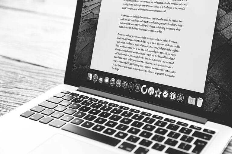 A laptop displaying "How To Get Your Blog Noticed" on a wooden table.