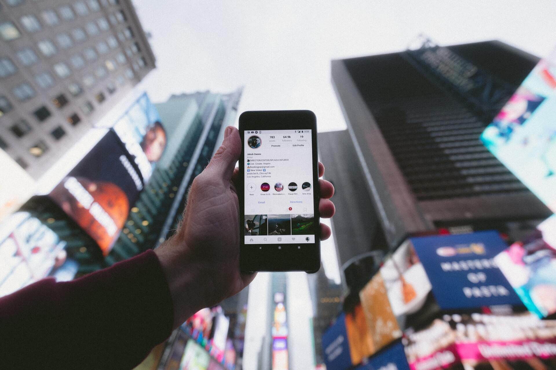 A person holding up an instagram phone in front of a city while showcasing their personal blog.