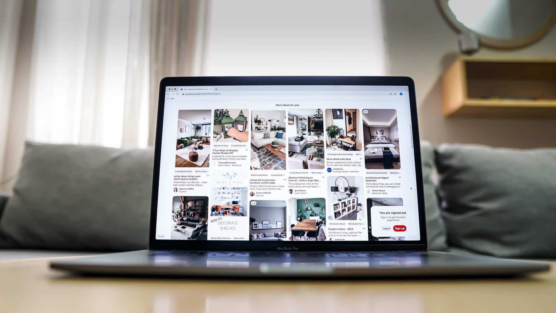 A laptop with pictures on it is being utilized in a living room for implementing Pinterest to promote a blog.