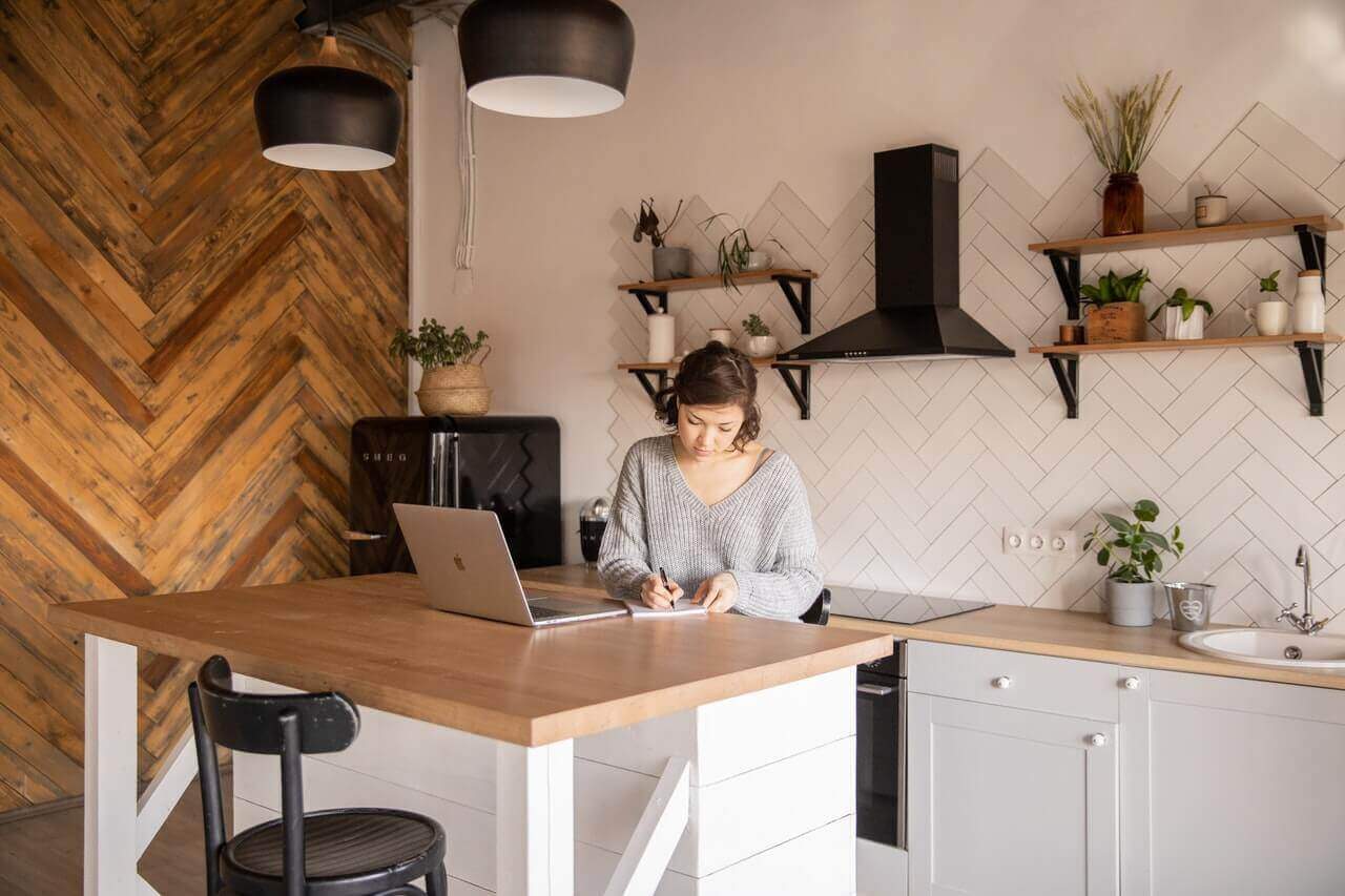 A copywriter working diligently on her laptop in a cozy kitchen.