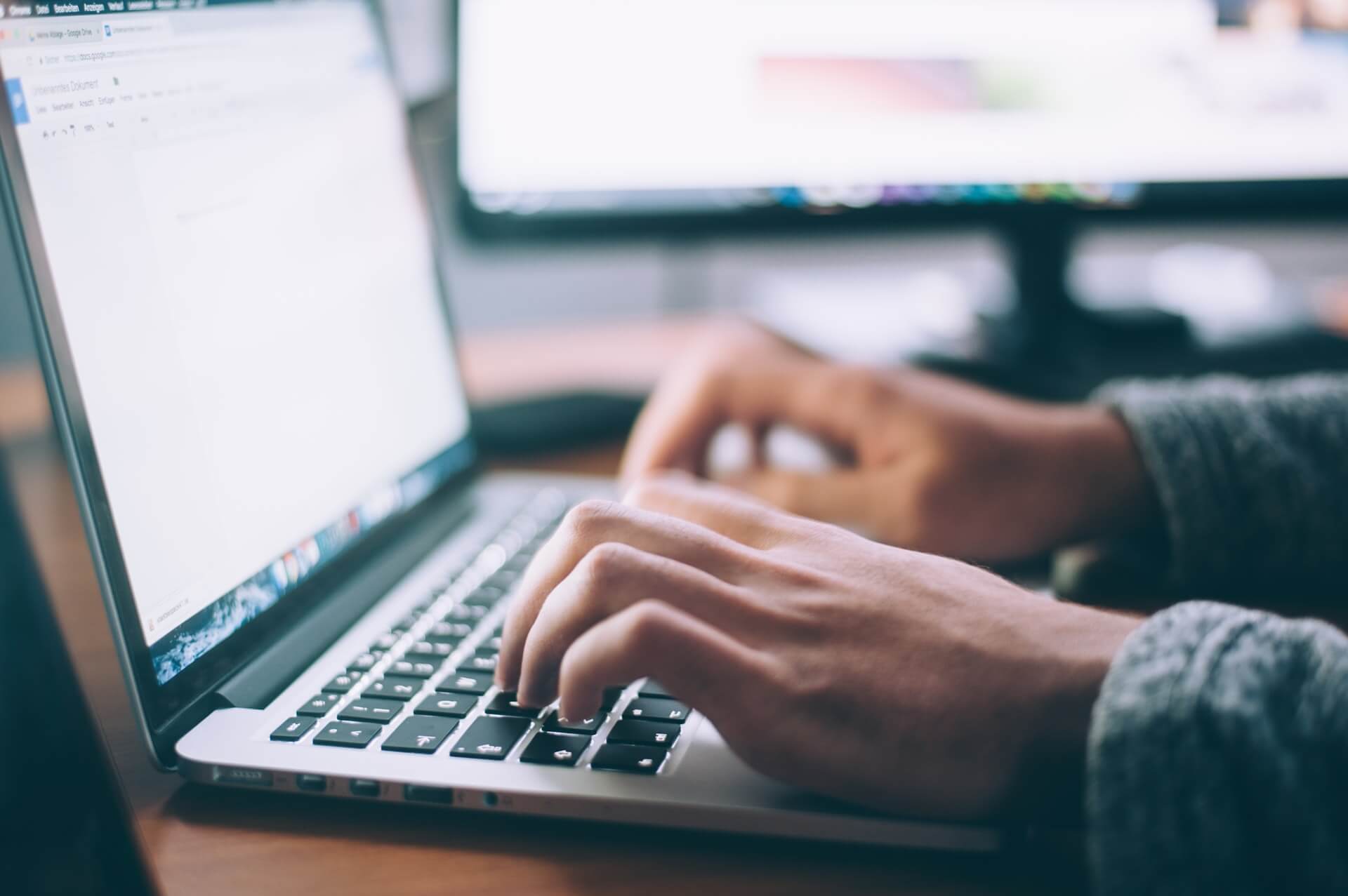 A person using a laptop computer to blog and seeking a Blogging Guide.