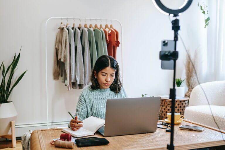 A woman working at a desk with a laptop, discussing the cost of blogging and essential knowledge.