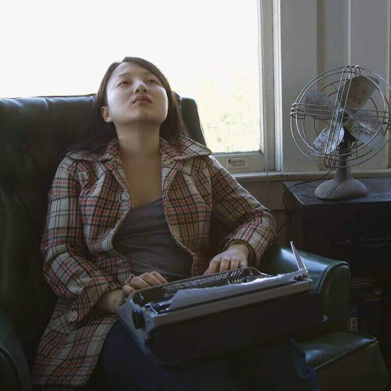A woman working from home, typing on a typewriter to earn money.