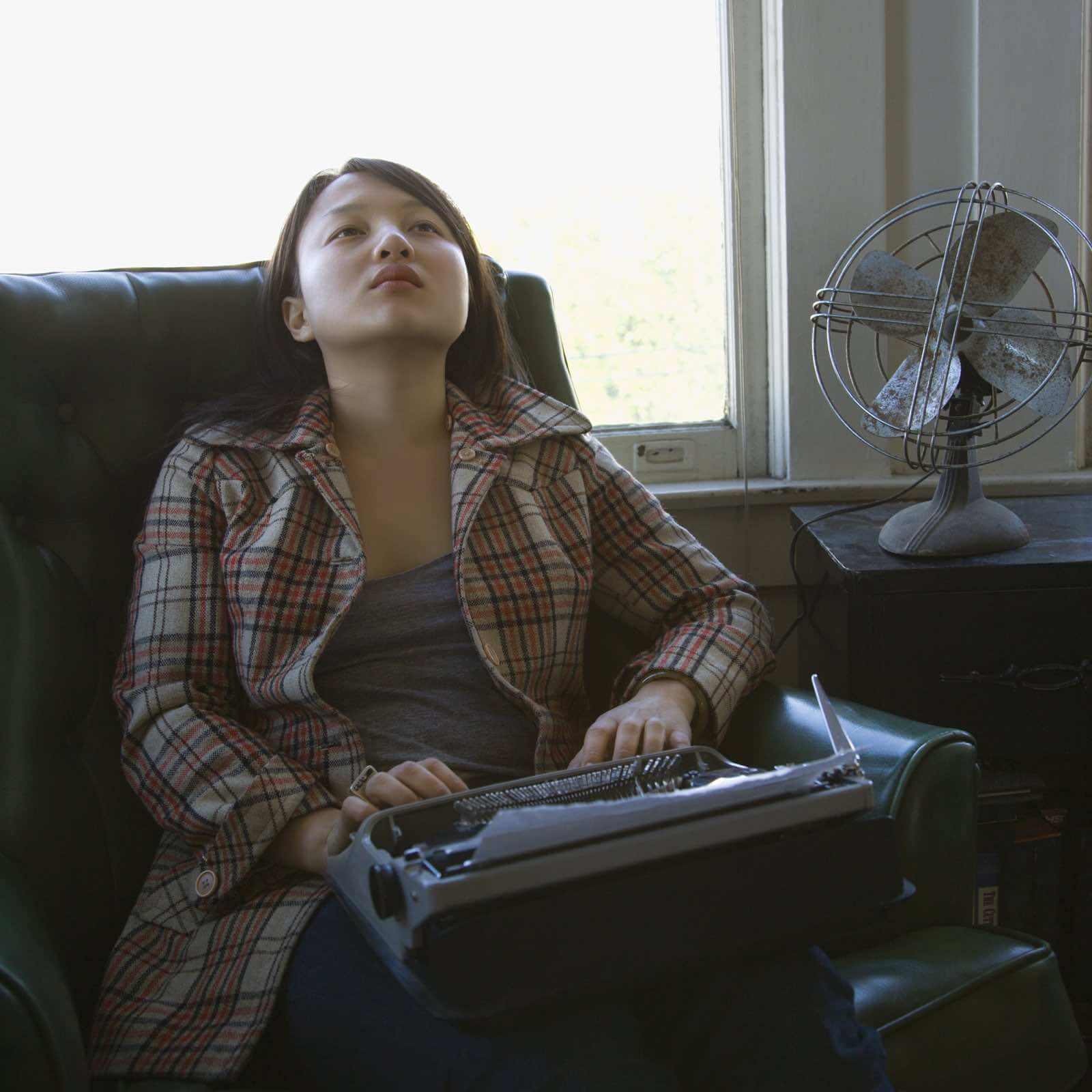A woman working from home, typing on a typewriter to earn money.