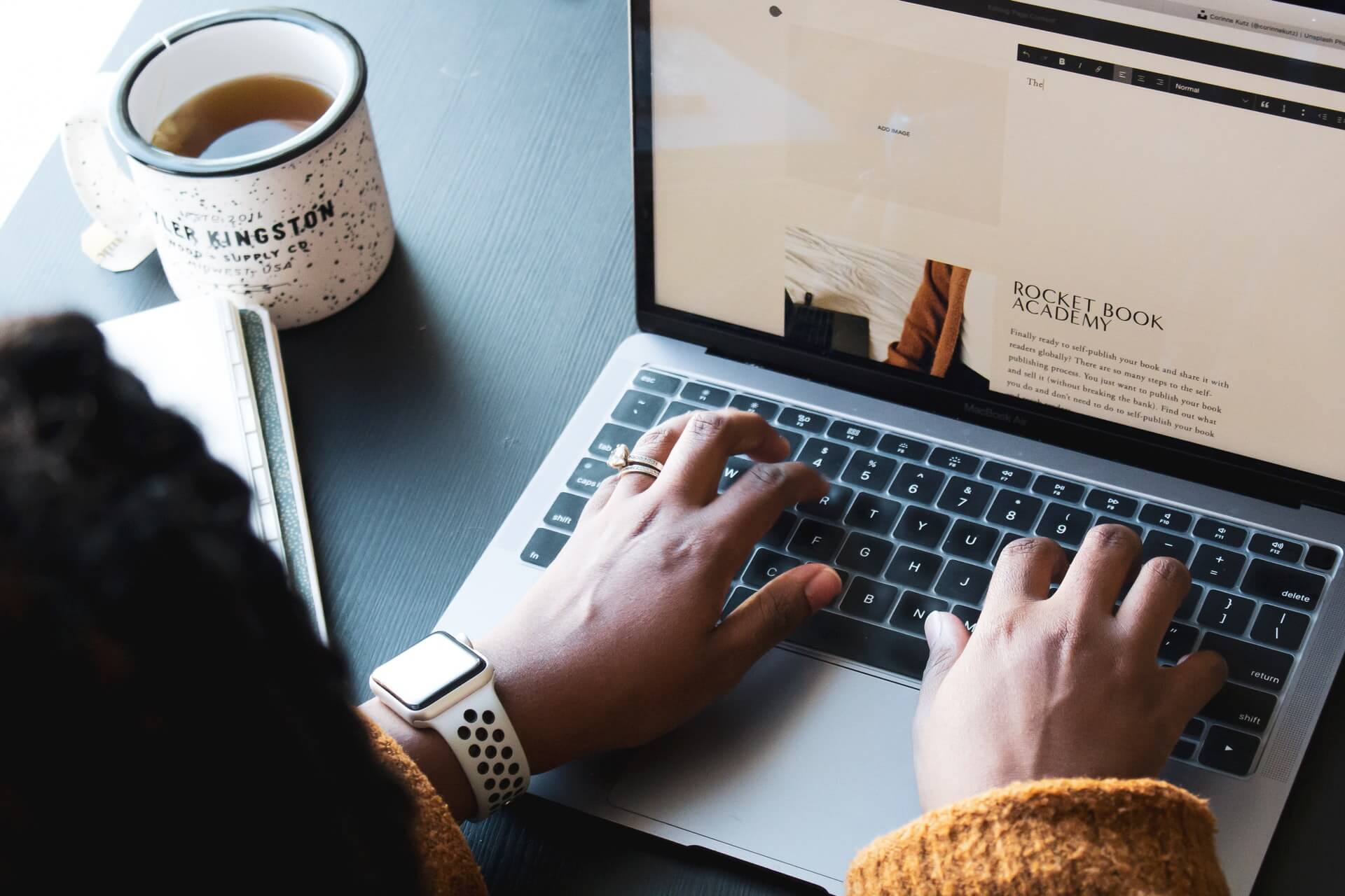 A woman typing on a laptop, blogging about making money in less than 6 months.