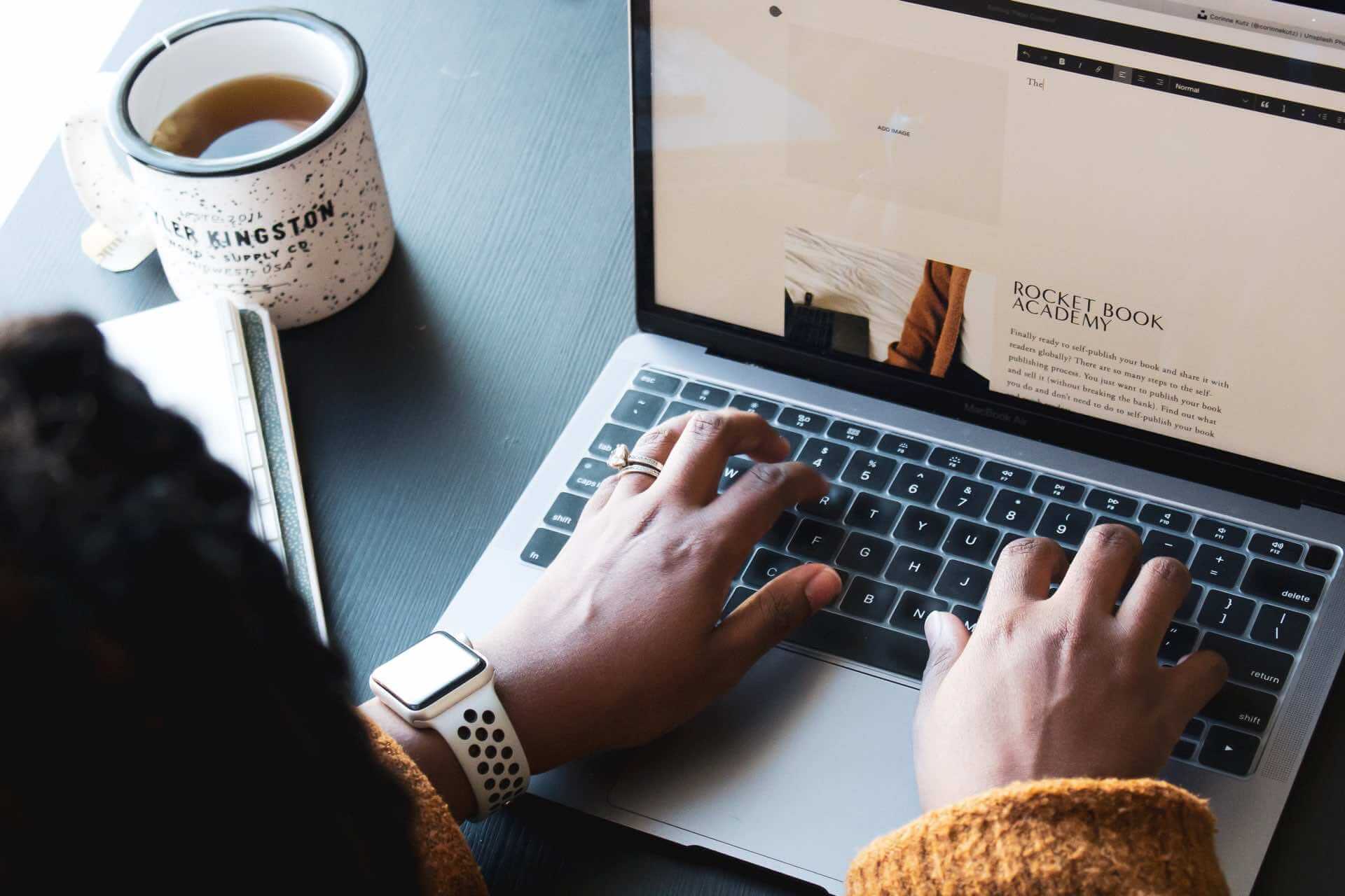 A woman typing on a laptop, evaluating copywriting rates.