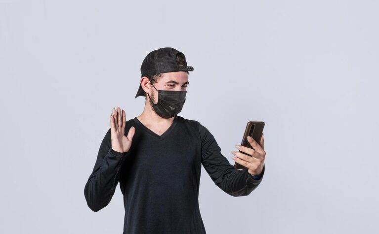A man showcasing a creative selfie technique while wearing a face mask, exploring ways to earn through OnlyFans without revealing his identity.